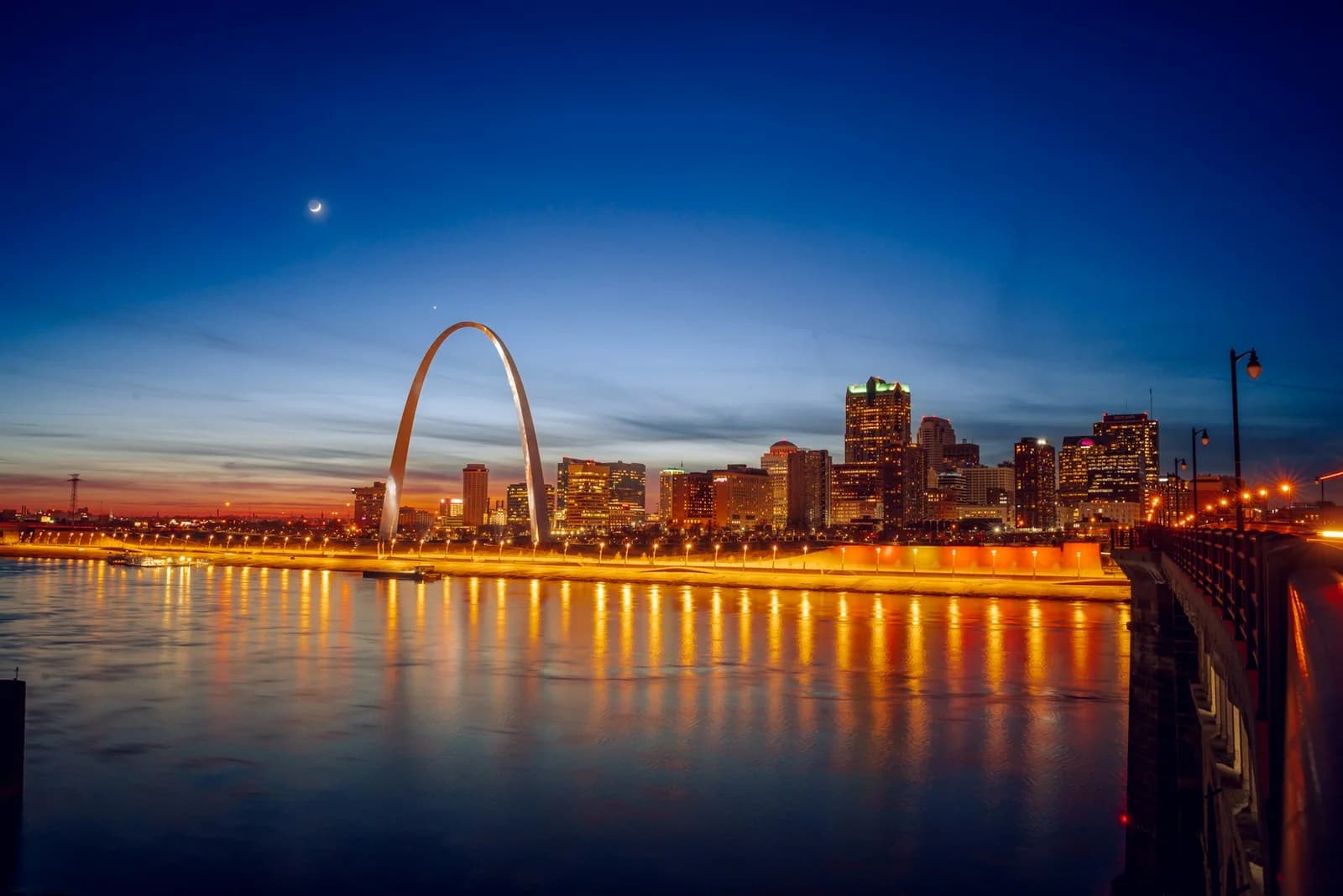 The Gateway Arch and St. Louis skyline across the river at blue hour.